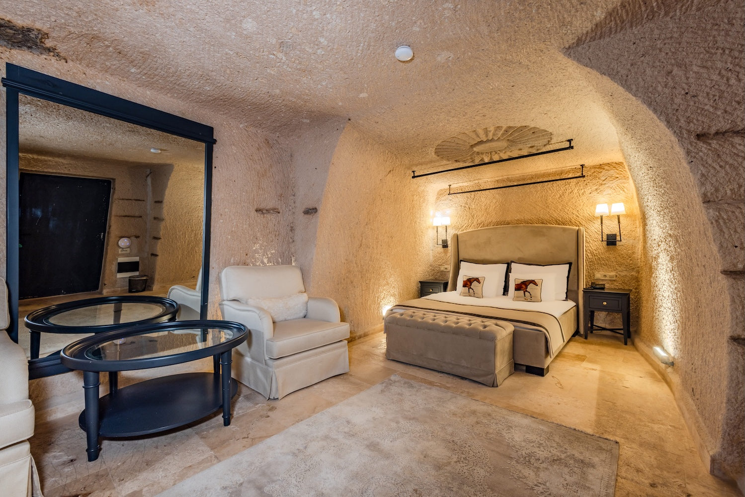 Luxury cave-style bedroom with bed, chairs, and decor.