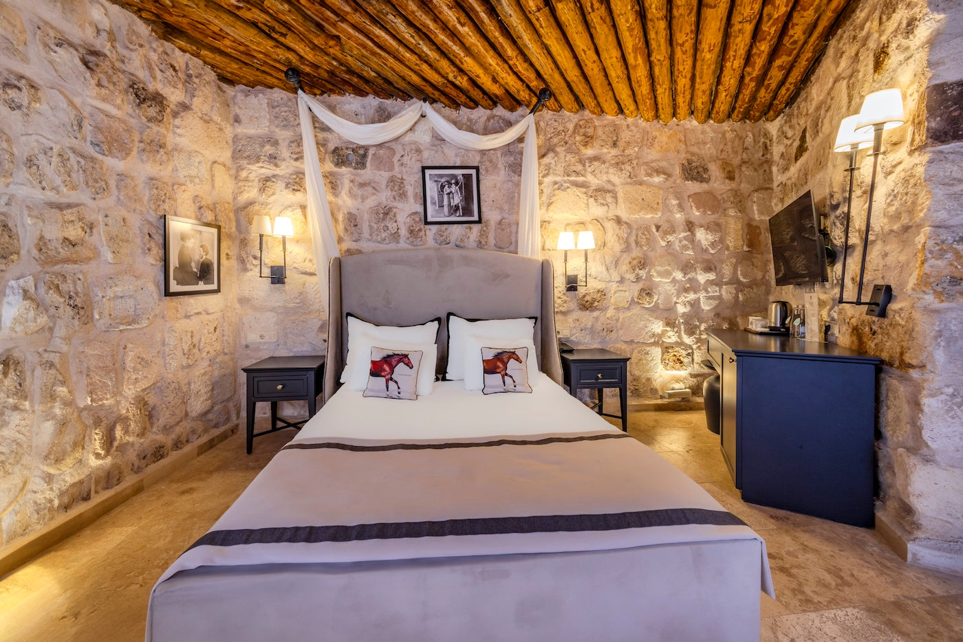 Bedroom with stone walls, wooden ceiling, and decorative pillows.