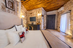 Bedroom with stone walls, wooden ceiling, and a desk.