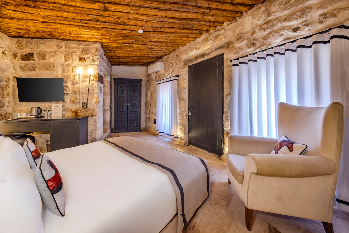 Luxury bedroom with stone walls, wooden ceiling, and a large bed.