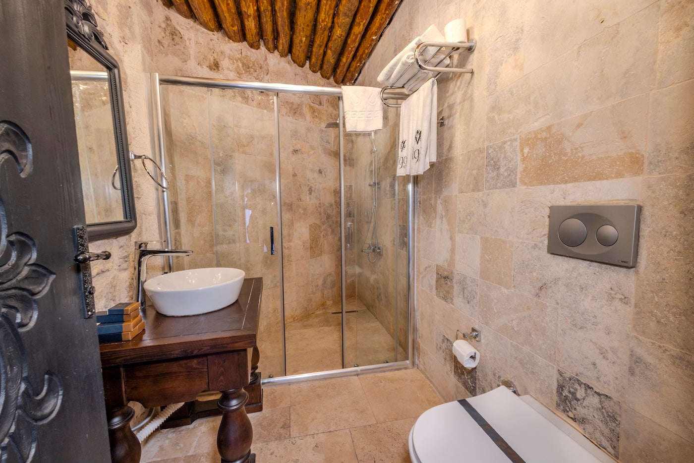 Bathroom with stone walls, shower, sink, and toilet.