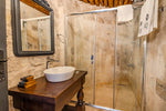 Bathroom with wooden vanity, white sink, and glass shower enclosure.